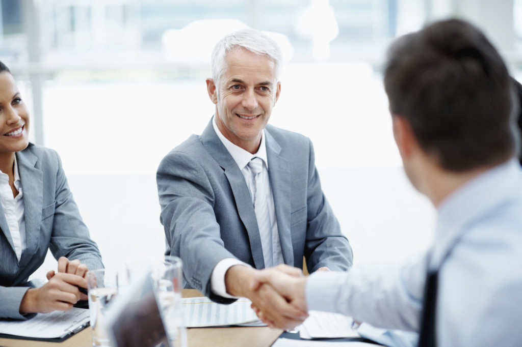 Businessmen Shaking Hands In A Group Setting