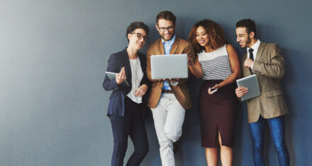Studio shot of a group of businesspeople using wireless technology together while standing in line against a gray background