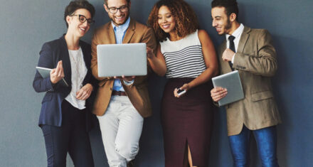 Studio shot of a group of businesspeople using wireless technology together while standing in line against a gray background